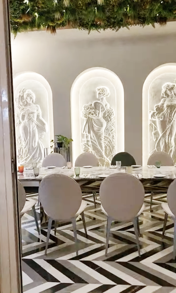 Interior dining area at Padam Restaurant in Tirana, showcasing ornate wall sculptures and elegant marble tables