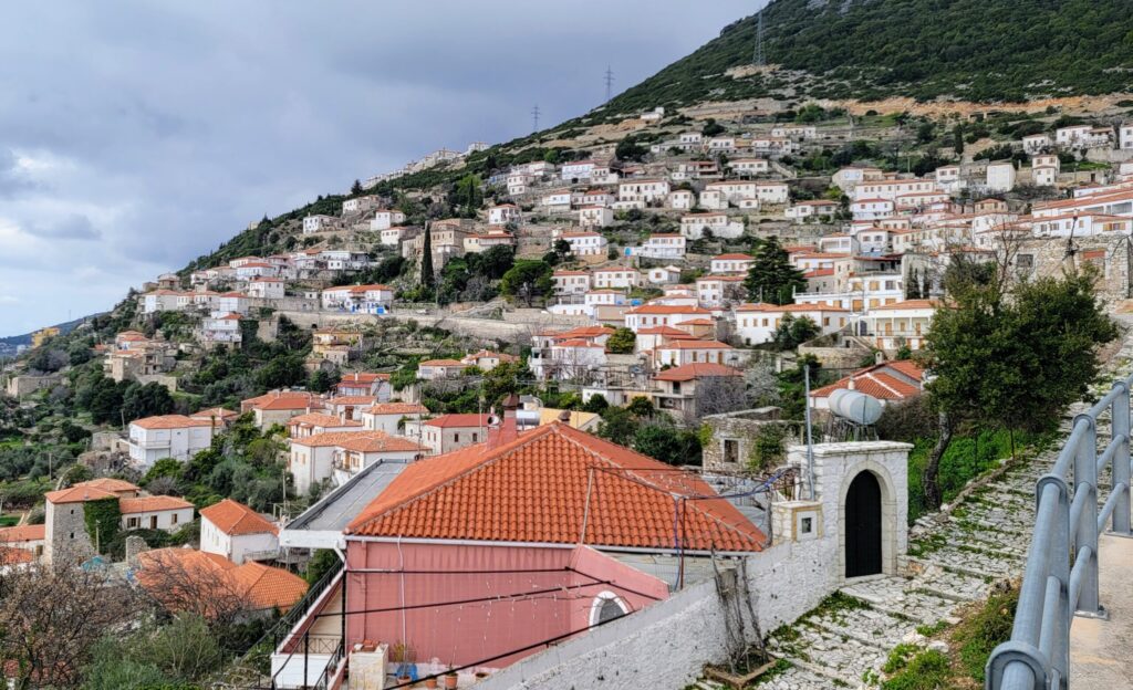 Panoramic view over the hillside city in Albania, showing traditional stone-roofed houses and the surrounding mountains.