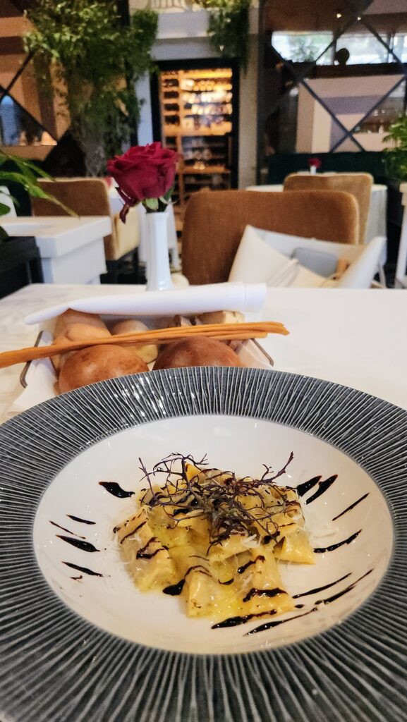Plate of pasta with microgreens and balsamic glaze, photographed from above in a restaurant setting.