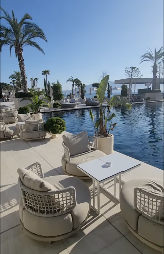 Elegant poolside lounge seating at Gjurma Restaurant Cafe in Vlorë, featuring luxurious outdoor furniture and palm trees overlooking the sea.
