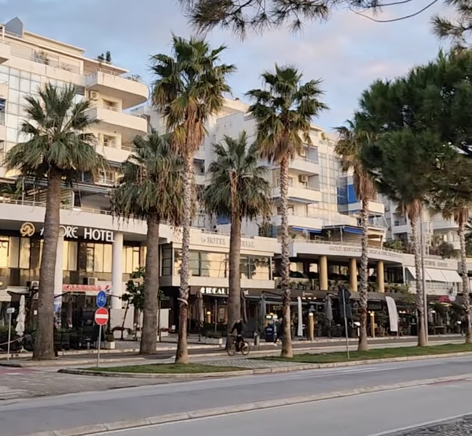 photo of lungomare promenade in vlore, albania with white buildings, wide streets, and tall palm trees