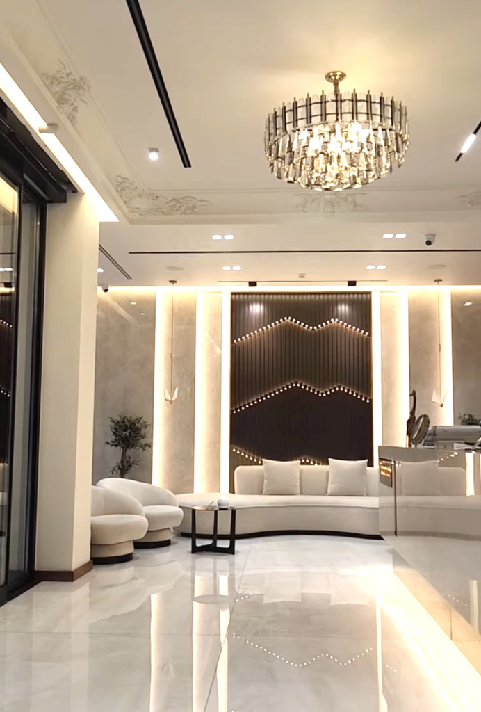 Modern, luxurious waiting area of the Haxhiu Medical Center in Vlorë, featuring white minimalist furniture and a grand chandelier.