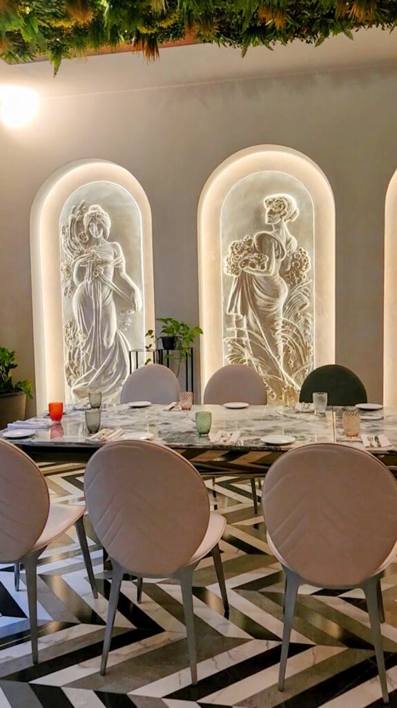Interior dining area at Padam Restaurant in Tirana, showcasing ornate wall sculptures and elegant marble tables