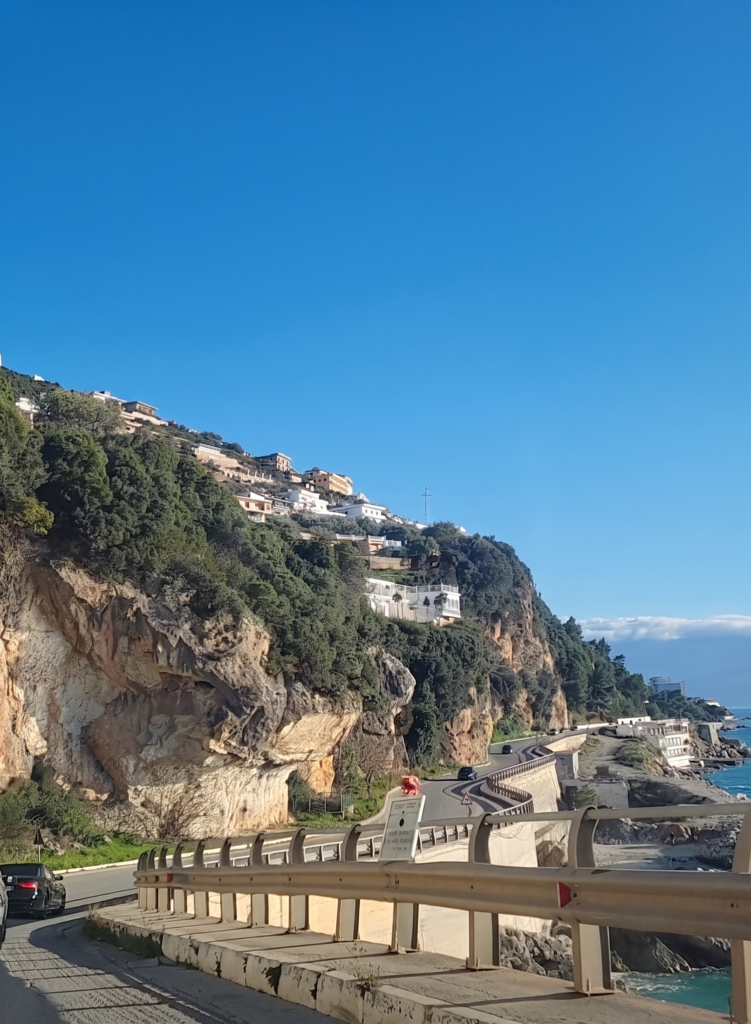 Scenic view of the rugged SH8 highway coastal drive along the Albanian Riviera, with limestone cliffs and clear blue skies
