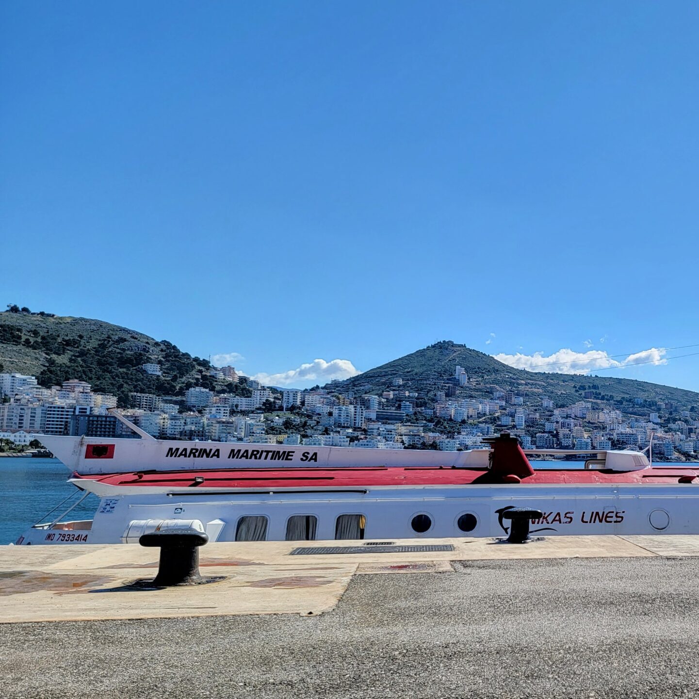 Large passenger ferry docked along the shoreline in Sarandë under a clear blue sky.